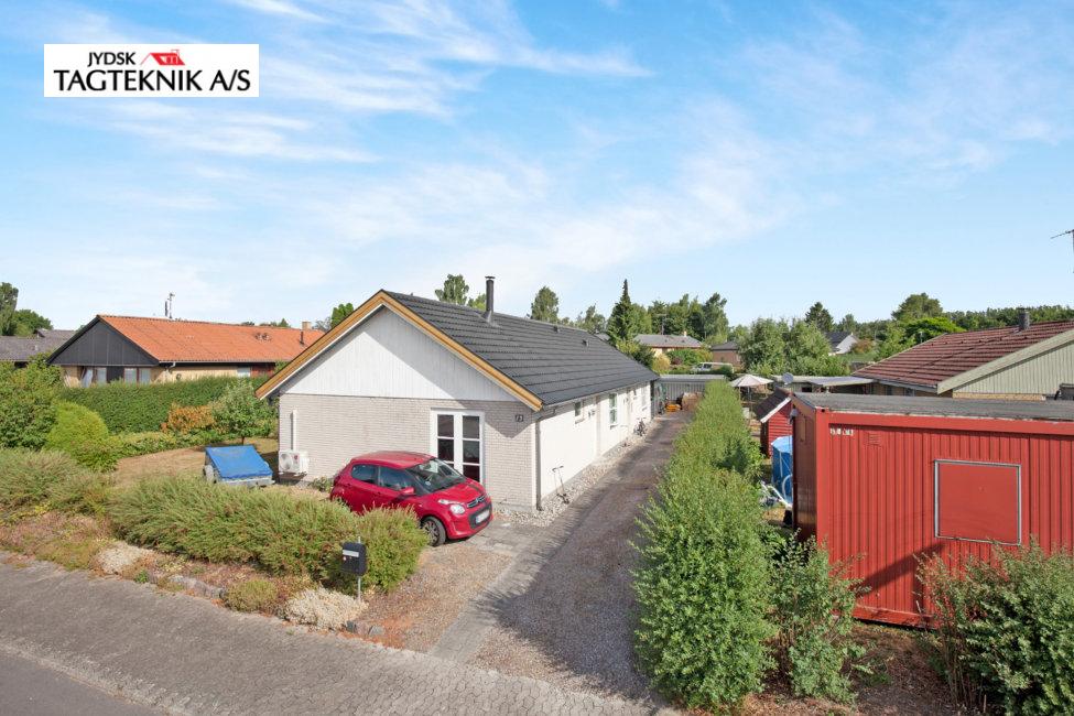 Grå murstens villa med indkørsel og have