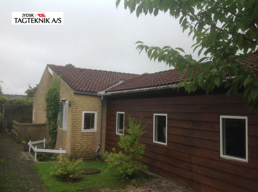 Gul murstensvilla med tilbygning af mørk træ